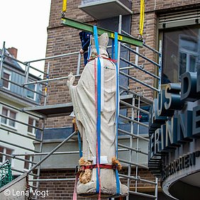 Augustinus-Statue hängt im Kran vor Krankenhaus Eingang