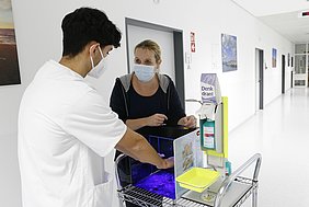 Pfleger überprüft die richtige Händedesinfektion mithilfe einer UV-Lampe