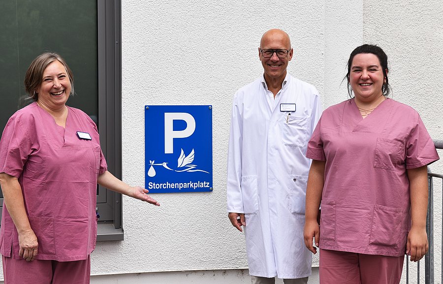 Marzena Koprowski, Prof. Dr. Jan Schmolling und Hannah Faourie zeigen den neuen Storchenparkplatz am Krankenhaus der Augustinerinnen